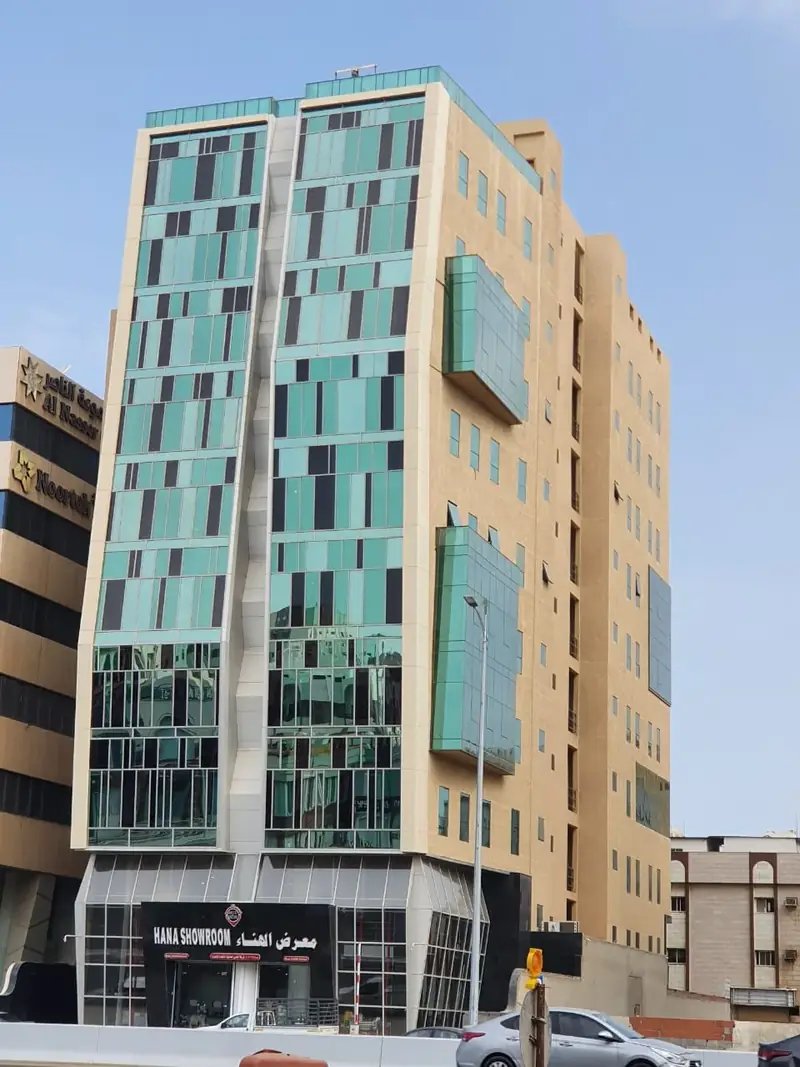 مبنى معرض الهناء متعدد الطوابق بواجهة زجاجية خضراء وواجهة عرض زجاجية في الدور الأرضي